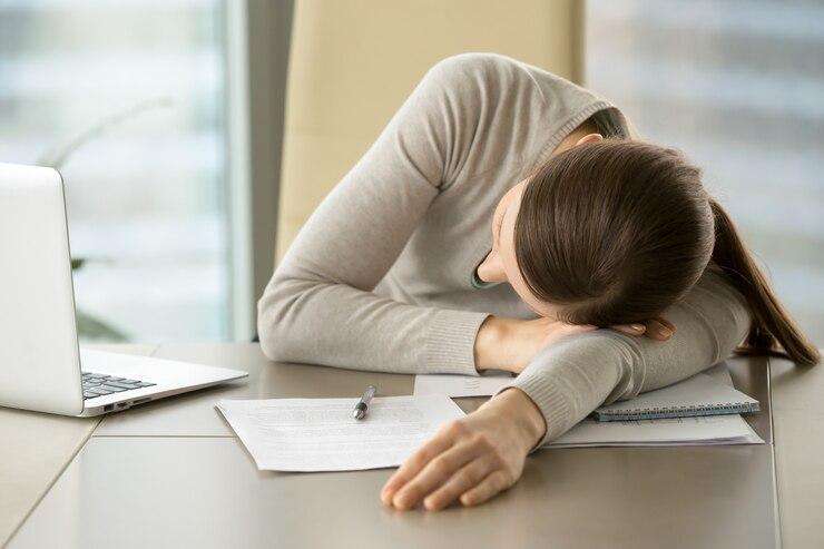 Female employee sleeping at her desk in the office