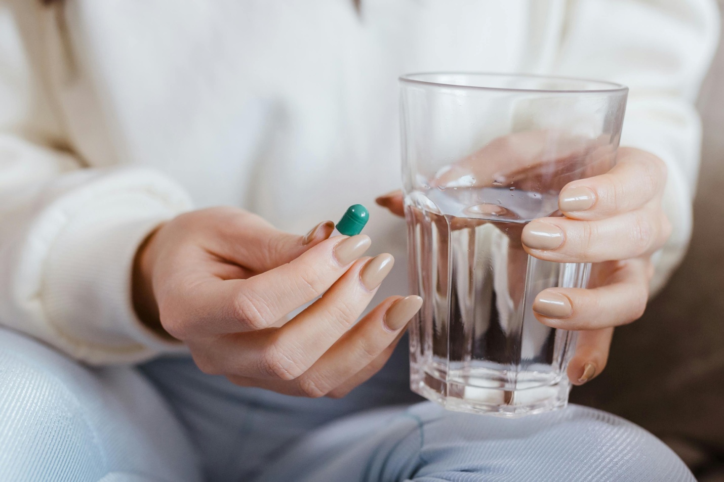 A picture of a person holding a pill and a glass of water