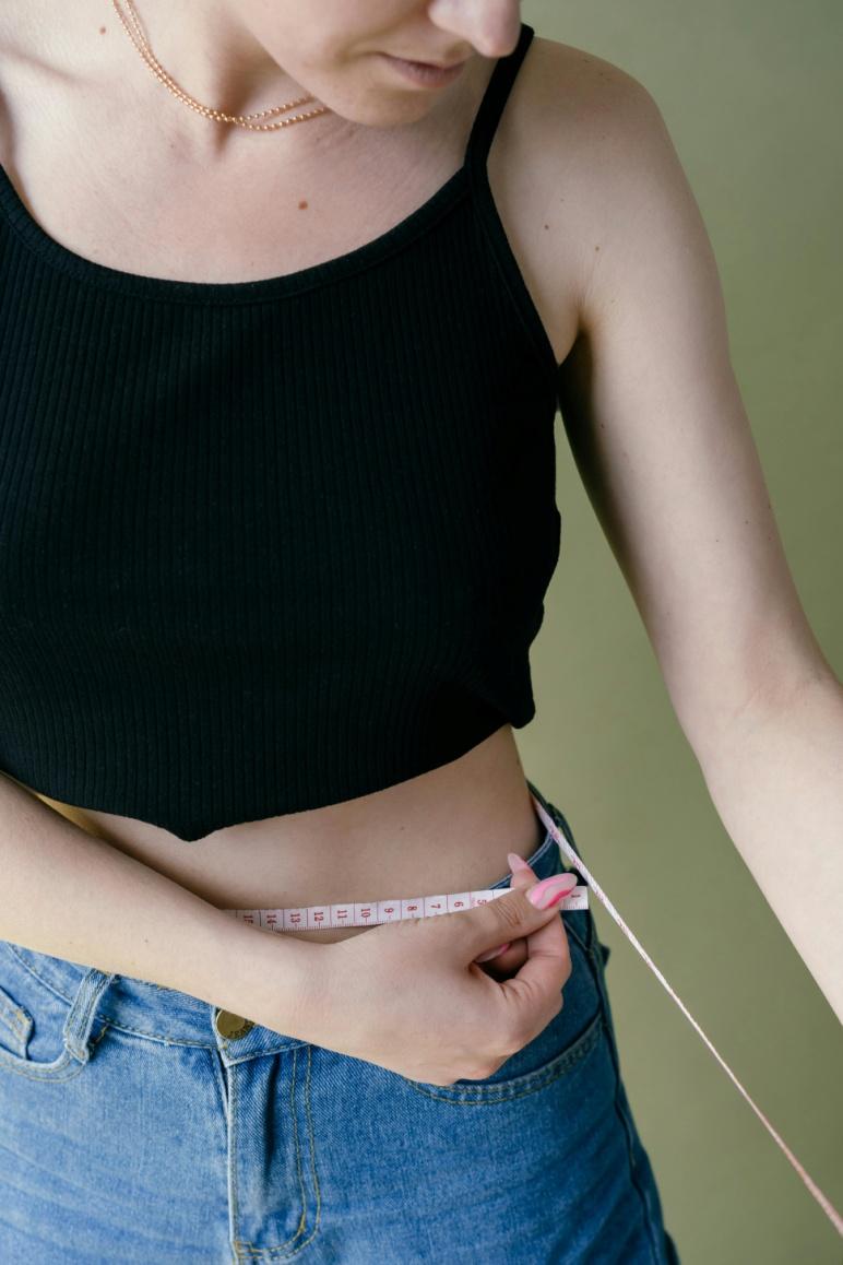 A picture of a person measuring their waist with a measuring tape