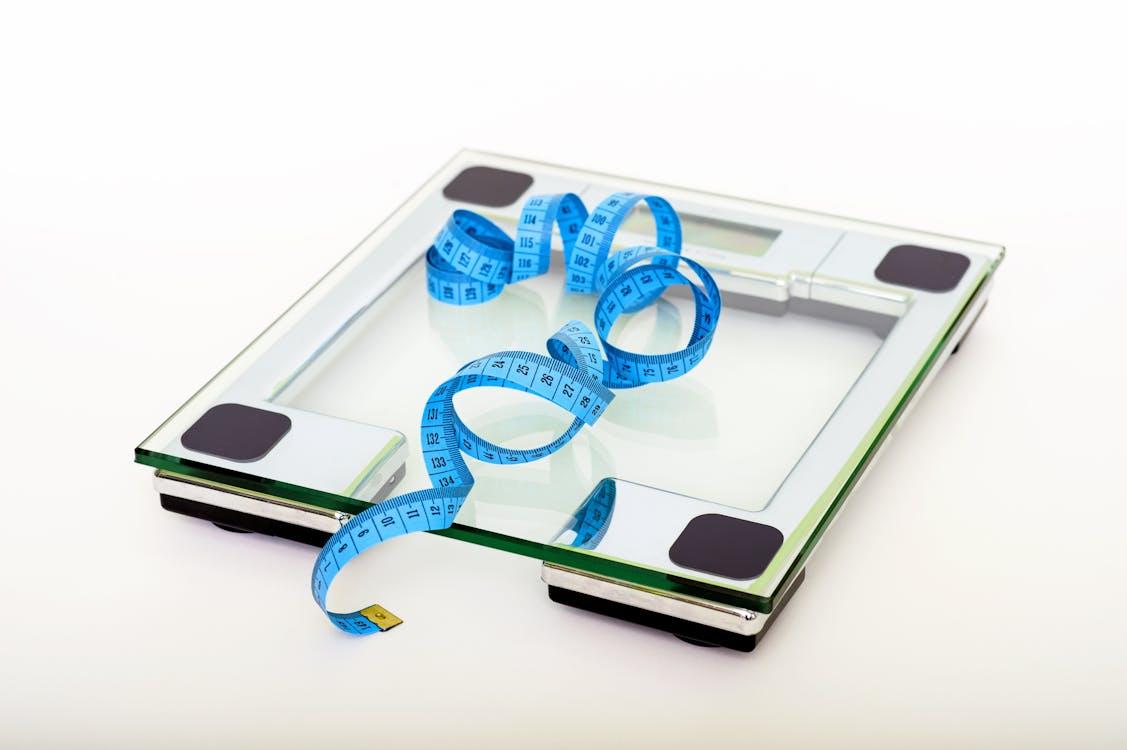A blue measuring tape resting on a glass digital scale