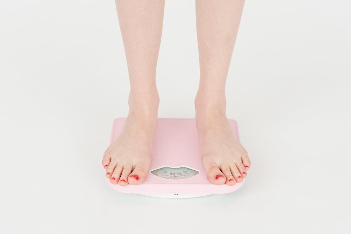 Person standing on weighing scale to track weight loss progress