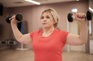 Woman lifting dumbbells during a strength training workout to support healthy weight loss and muscle maintenance